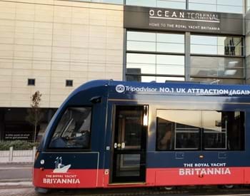 Tram featuring advertising for The Royal Yacht Britannia in front of Ocean Terminal building