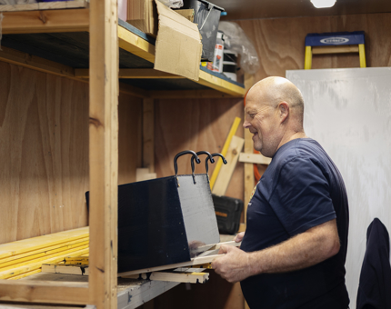 A Facilities Officer is in the workshop making a herb planter. 