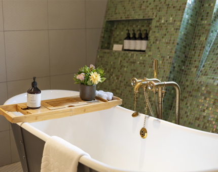 A roll top bath is situated in a bathroom with green wall tiles aboard Fingal. 