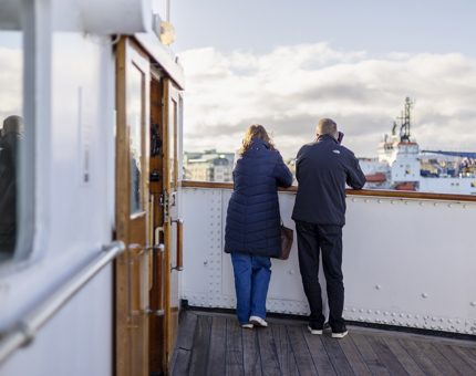 Two visitors look out into the Port of Leith from Britannia's Bridge as they listen to their audio guide handsets. 