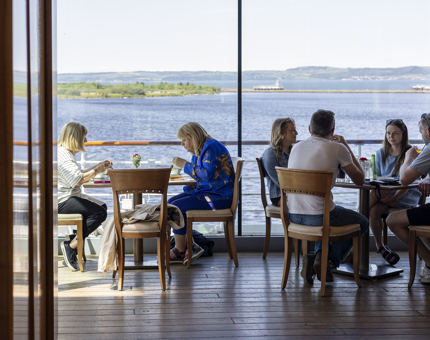 Tables of visitors enjoying drinks and lunch in Britannia's Royal Deck Tearoom. 