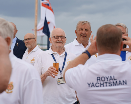 A group of smiling Royal Yachtsmen standing on the Verandah Deck. 