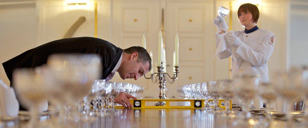 Two men setting a table in the State Dining Room. 