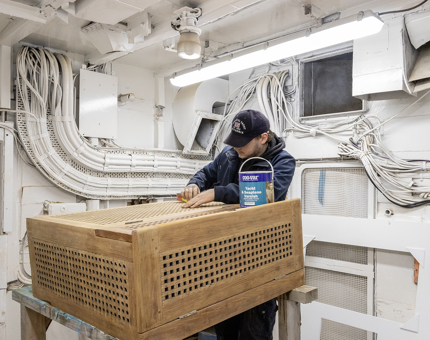 A man varnishing a wooden rope box. 