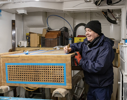 A man taping up the latticework on a rope box in the Workshop. 