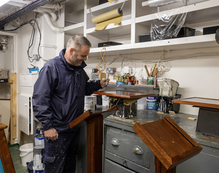 A man varnishing the wooden menu stands for the Royal Deck Tearoom.