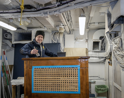 A man from the Maintenance team varnishing a large wooden rope box. 