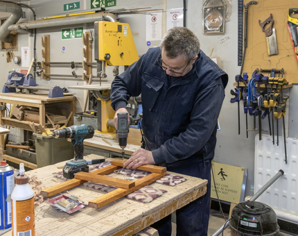 Man in blue jacket working with tools 