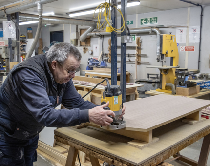 Man in blue coat working with wood 