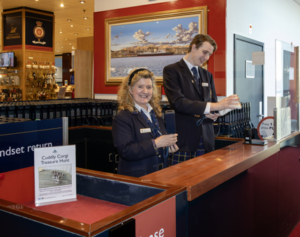Two Visitor Assistants cleaning audio tour handsets in the Visitor Centre. 