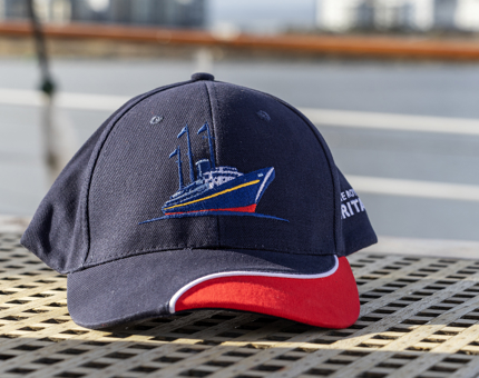 A navy blue and red baseball cap embroidered with the Britannia logo. 