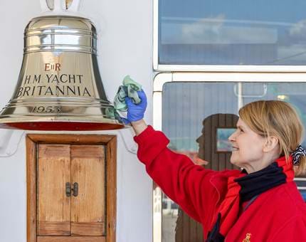 A woman from the Housekeeping Team polishing The Royal Yacht Britannia's Bell. 