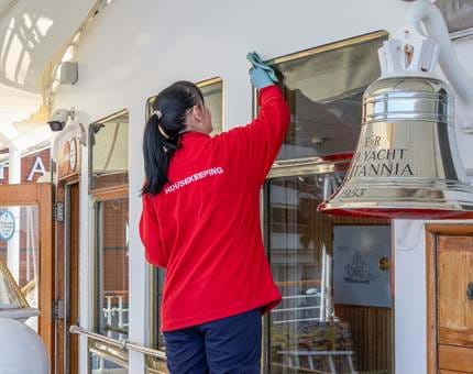 A member of the Housekeeping Team polishing the brasswork outside the Sun Lounge windows. 