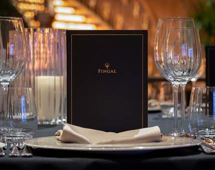 A table setting in Fingal's Ballroom with a menu, glasses and linen napkin. 