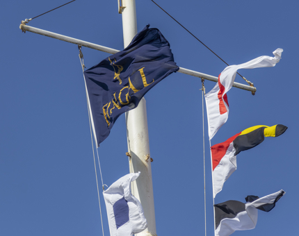Brightly coloured flags flying in the freeze from a mast on Fingal. 
