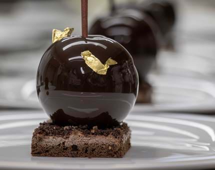 A close-up of a Black Forest Gateau dessert covered with gold leaf decoration. 