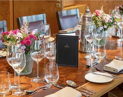 A close-up of a table setting in Fingal's Bridge. There are lots of different glasses on the table, floral arrangements, plates and cutlery. 