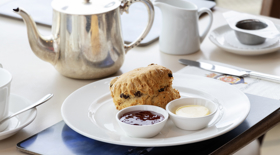 A table in the Royal Deck Tearoom containing a scone, jam, cream and a silver pot of tea.  A table in the Royal Deck Tearoom containing a scone, jam, cream and a silver pot of tea.