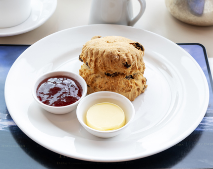 A fruit scone with jam and butter.