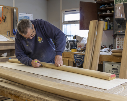 A member of the Maintenance team drawing out templates on wood. 