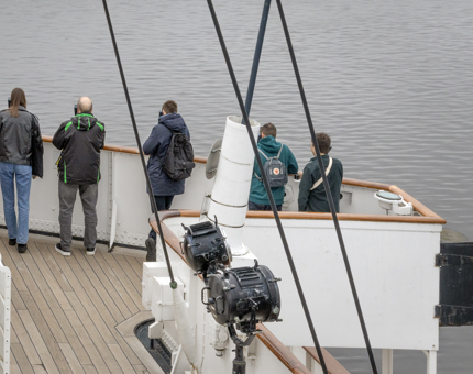 Visitors listening to audio handsets outside on the deck. 