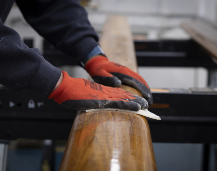 Red and black gloved hands sanding the handrail.