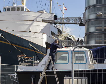 A man painting the top of the Activity Boat. 