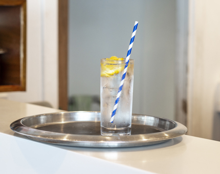A glass of Gin and Tonic sitting on a silver tray. 