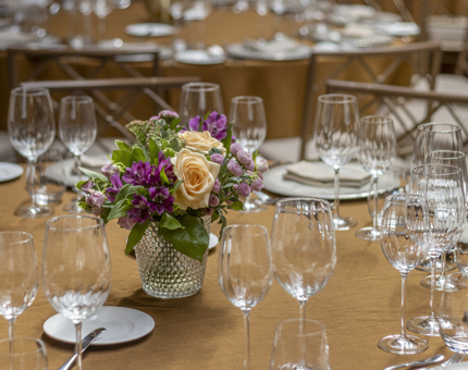 A table with glasses and a vase of pink and orange flowers. 