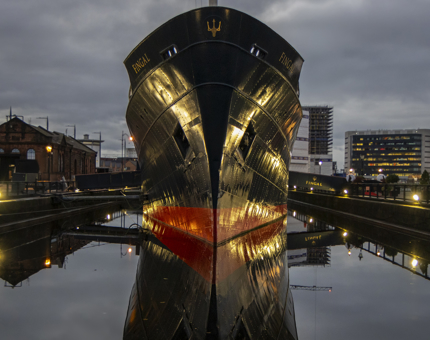 The front of Fingal, a ship,  reflecting in the water. 