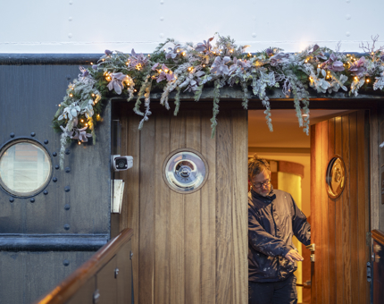 A man at the entrance of Fingal Hotel tidying up Christmas decorations. 