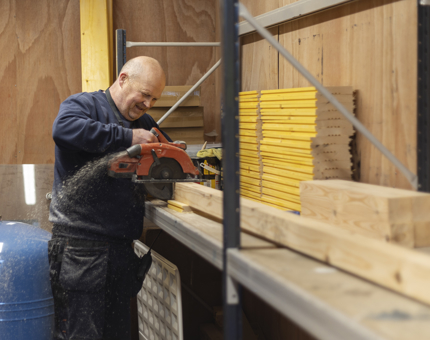 A Facilities Officer cutting wood to make planters. 