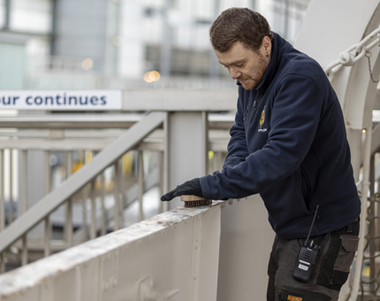 A Maintenance team member brushing the Port Side with a wire brush. 