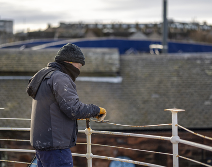 Aboard Fingal Hotel, railings on the deck are being prepared for painting. 
