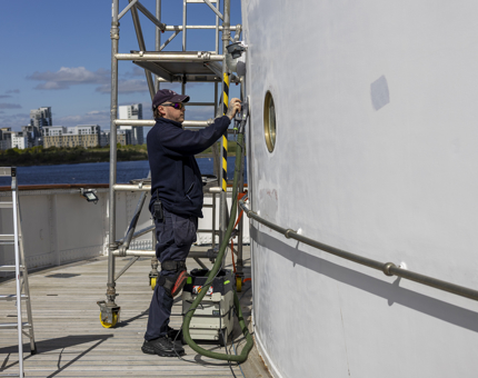 A Maintenance man sanding a wall aboard Britannia in the Port of Leith. 