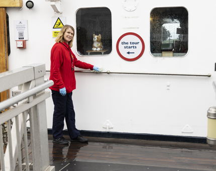 A Housekeeper is standing outside the Bridge polishing a handrail. 