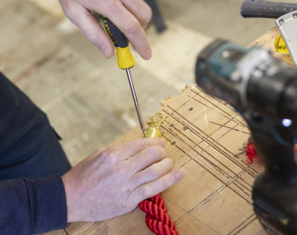 A close up of hands fixing a rope end which will go on the tour route. 