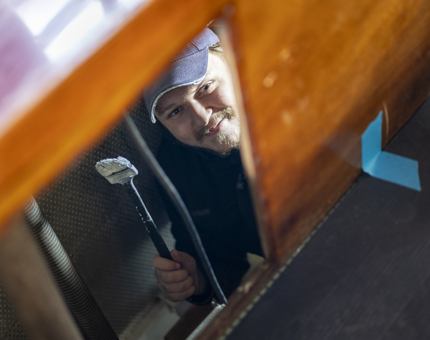 A maintenance man painting inside of the Royal Barge. 