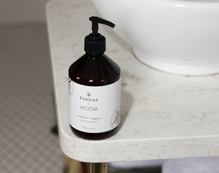 A bottle of MODM branded hand and body wash. It is sitting on the bathroom counter. 