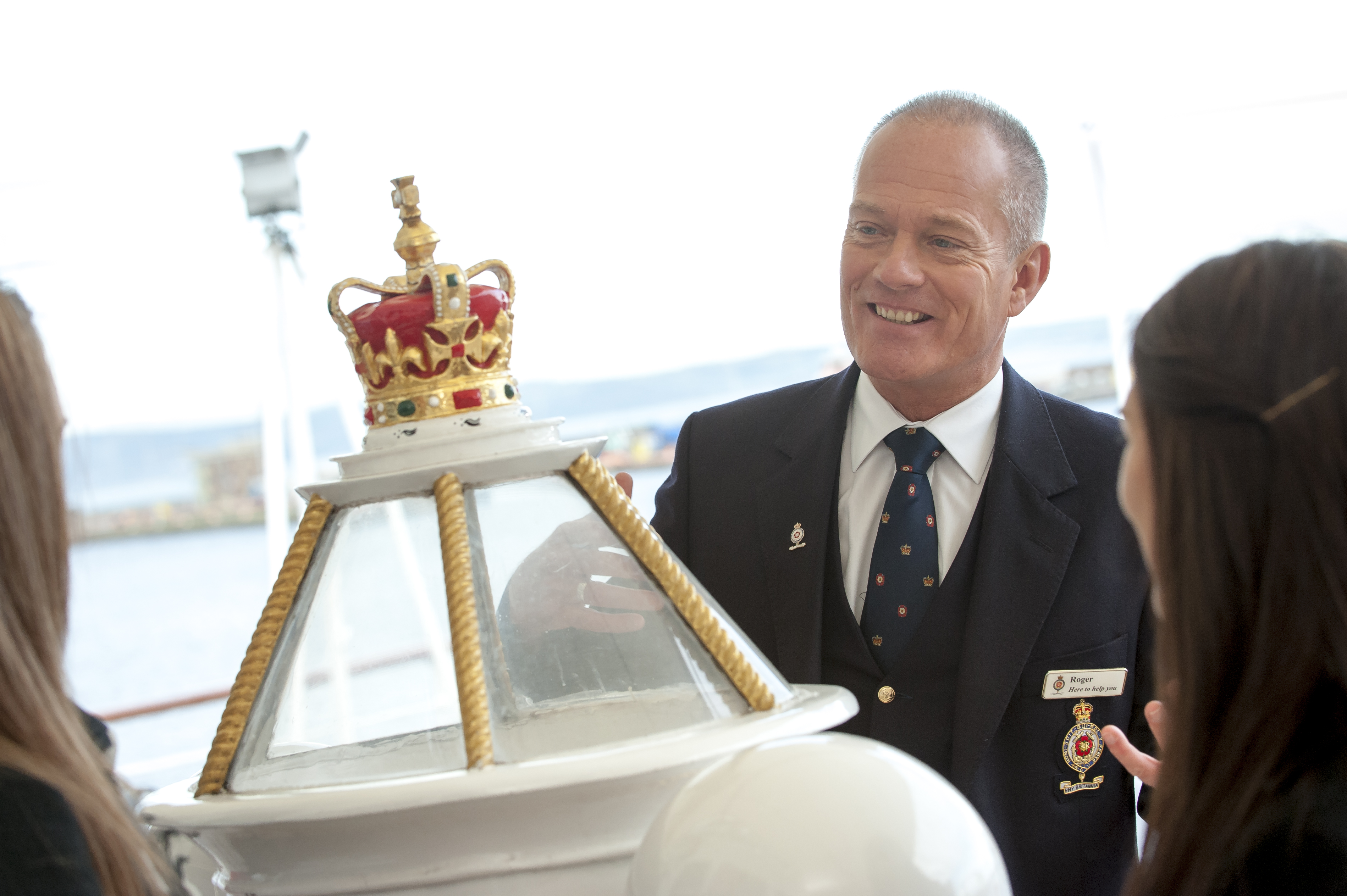 A Visitor Experience guide talking to visitors by the decorative binnacle. 