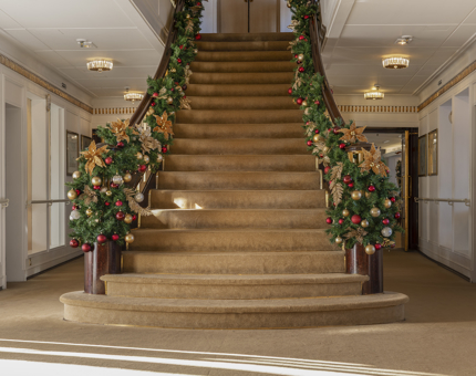The grand staircase aboard The Royal Yacht Britannia in Leith with Christmas wreaths draped over the bannisters. 