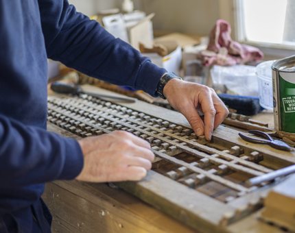 A close up of hands replacing sections of damaged wooden slats from the Verandah Deck. 