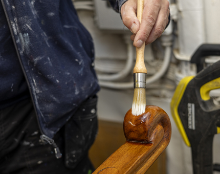  A close up of a Maintenance man varnishing the curved end of a handrail. 