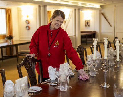A Housekeeper is wiping a dining table in the State Dining Room. 