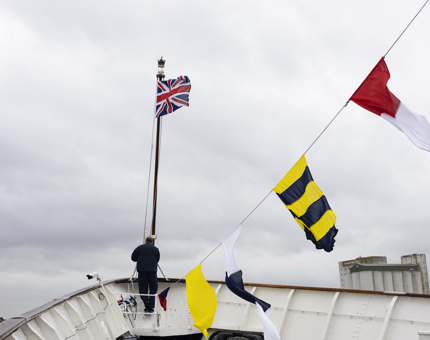 A Maintenance man is securing ropes beneath the flag pole at Britannia's Bow. 