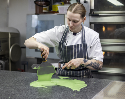 A chef is in Britannia's Galley tempering green coloured chocolate. 