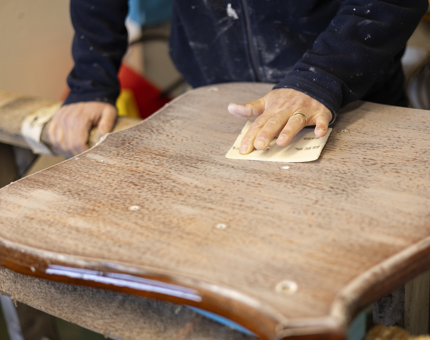 A close up of a wooden crest being sanded. 
