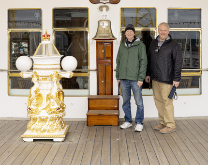 Two Visitors pose for a photo at Britannia's Bell on The Verandah Deck. 