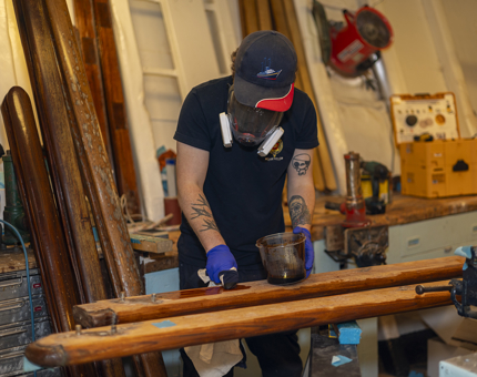 A man varnishing wooden handrails in the workshop.