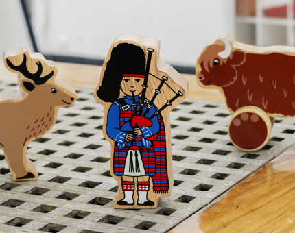 Wooden Scottish toys from the Shop. There is a bagpipe player, Highland cow and stag. 
